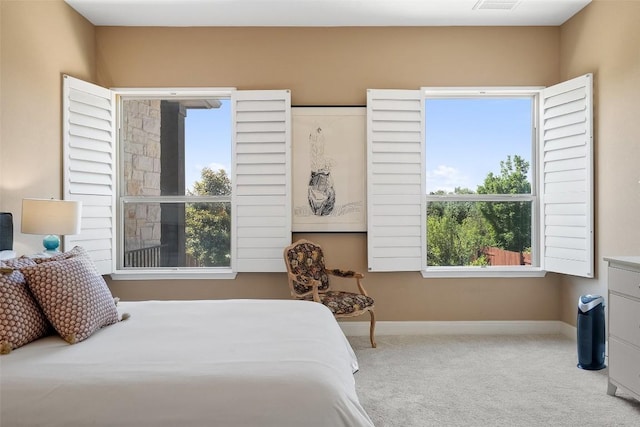 carpeted bedroom featuring multiple windows and baseboards