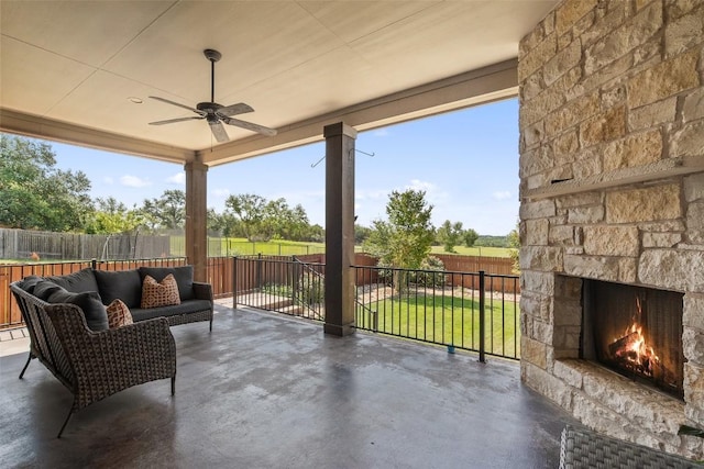 view of patio featuring a fenced backyard, an outdoor living space with a fireplace, and a ceiling fan