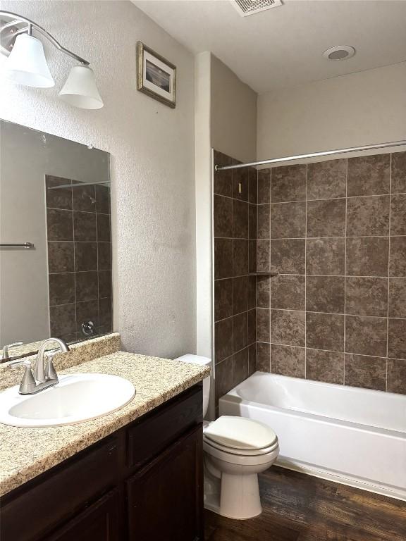 253 Eagle Brook Ln, Buda, TX 78610 - full bathroom featuring wood finished floors, vanity, a textured wall, and tub / shower combination