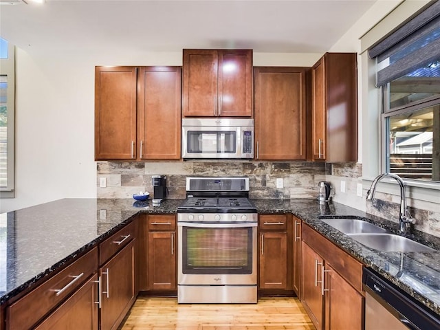 614 Terrell Hill Dr Unit B, Austin, TX 78704 - kitchen featuring appliances with stainless steel finishes, dark stone counters, backsplash, and light wood-style floors