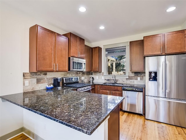 614 Terrell Hill Dr Unit B, Austin, TX 78704 - kitchen featuring stainless steel appliances, a peninsula, dark stone counters, tasteful backsplash, and recessed lighting
