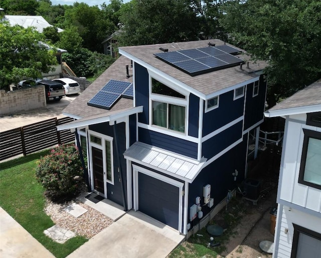 view of front facade with roof with shingles, roof mounted solar panels, an attached garage, a standing seam roof, and metal roof