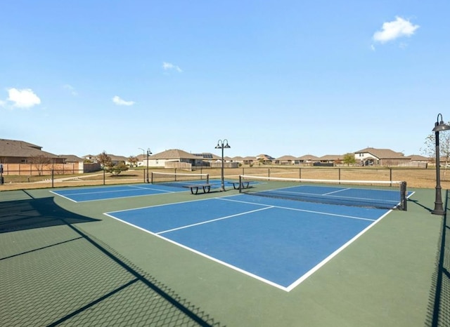 view of tennis court with fence and a residential view