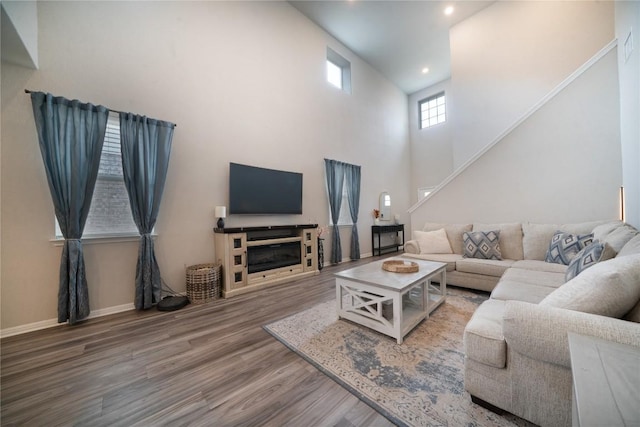 living area with wood finished floors, stairway, recessed lighting, a high ceiling, and a fireplace