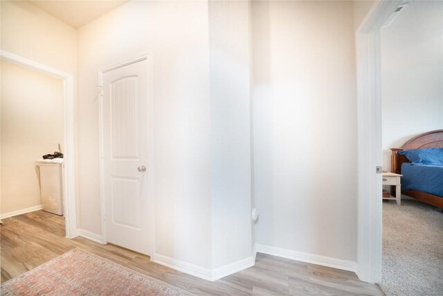 hallway with light wood-style flooring and baseboards