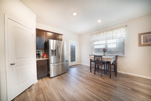 kitchen featuring stainless steel fridge, light wood finished floors, baseboards, dark brown cabinets, and recessed lighting