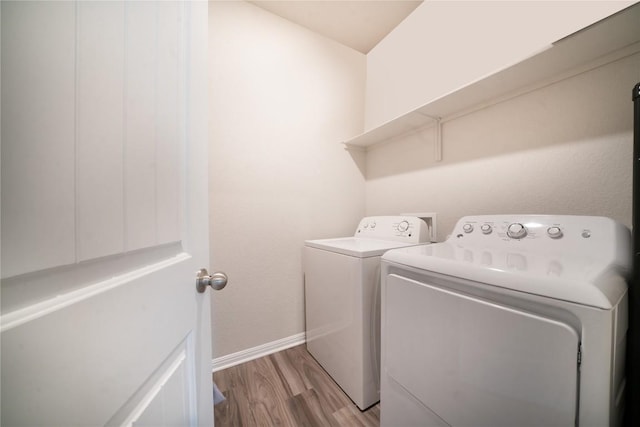 clothes washing area featuring washer and clothes dryer, light wood finished floors, and baseboards