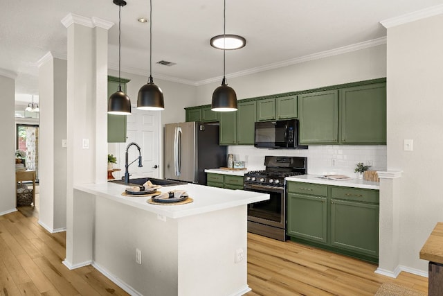 kitchen with green cabinetry, stainless steel appliances, a sink, crown molding, and decorative backsplash