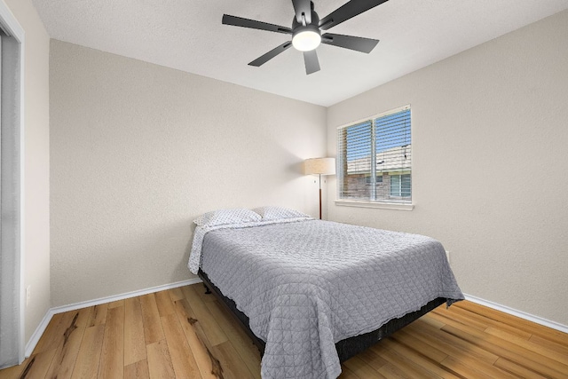 bedroom with baseboards, wood finished floors, and a ceiling fan