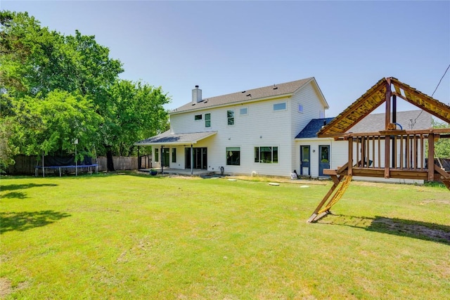 back of house featuring a trampoline, a chimney, and a patio