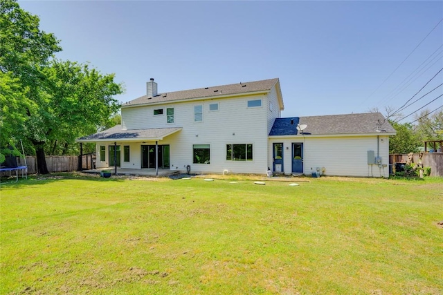 rear view of property featuring a trampoline, a chimney, and a patio area