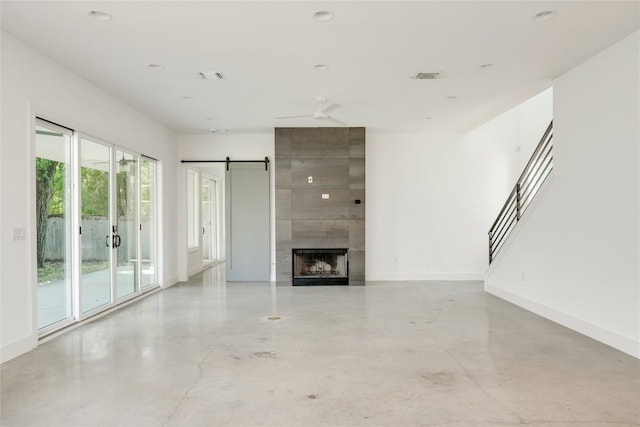 1305 Village W Dr, Austin, TX 78733 - unfurnished living room with concrete floors, a ceiling fan, a tile fireplace, and stairs