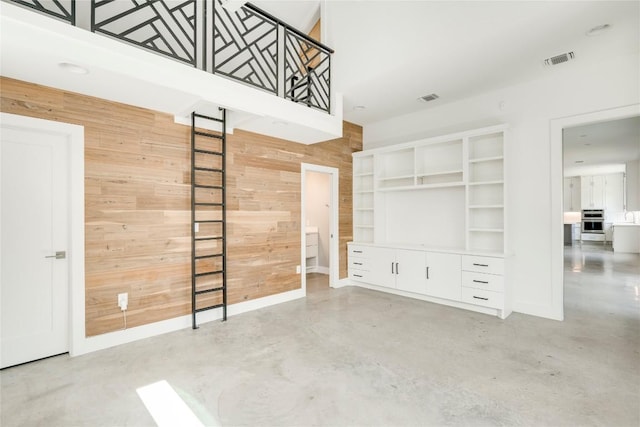 empty room with finished concrete flooring, wooden walls, and baseboards