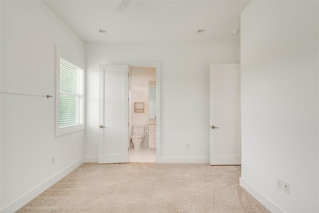 unfurnished bedroom featuring carpet, baseboards, and ensuite bathroom