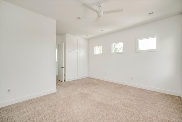 spare room featuring ceiling fan, baseboards, and light colored carpet