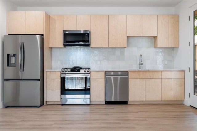 kitchen with appliances with stainless steel finishes, light brown cabinetry, and light countertops