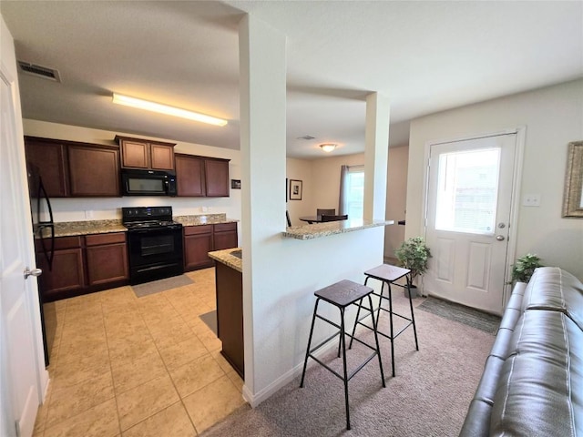 336 Farmer Ln, Jarrell, TX 76537 - kitchen featuring black appliances, a breakfast bar area, light stone countertops, and a peninsula
