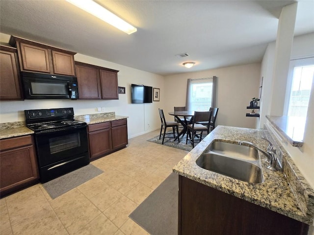 336 Farmer Ln, Jarrell, TX 76537 - kitchen with black appliances, a sink, light stone counters, dark brown cabinetry, and light tile patterned floors