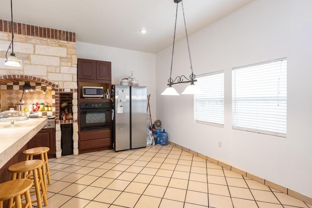 176 Old Lexington Rd Unit C, Elgin, TX 78621 - kitchen with appliances with stainless steel finishes, light countertops, a kitchen bar, decorative light fixtures, and light tile patterned floors