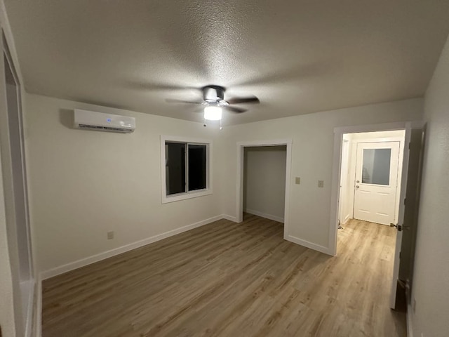 176 Old Lexington Rd Unit C, Elgin, TX 78621 - empty room featuring a wall unit AC, ceiling fan, light wood-style flooring, and a textured ceiling