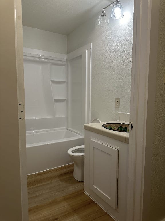 176 Old Lexington Rd Unit C, Elgin, TX 78621 - full bath with wood finished floors, shower / bathtub combination, and a textured wall
