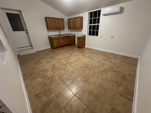 176 Old Lexington Rd Unit C, Elgin, TX 78621 - kitchen featuring a wall mounted AC, brown cabinetry, vaulted ceiling, light countertops, and light stone finish floors