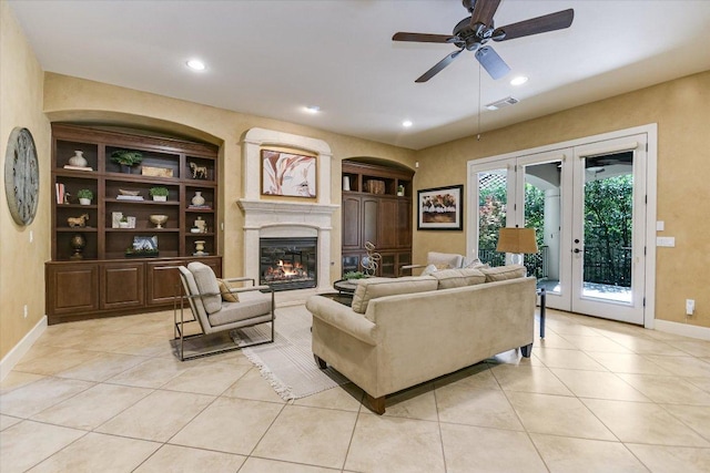 1036 Liberty Park Dr Unit 20, Austin, TX 78746 - living room featuring light tile patterned floors, ceiling fan, built in shelves, baseboards, and a glass covered fireplace