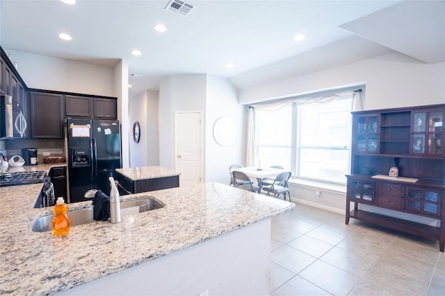 411 Tilly Ln, Buda, TX 78610 - kitchen featuring black refrigerator with ice dispenser, light stone countertops, dark brown cabinets, recessed lighting, and stainless steel microwave