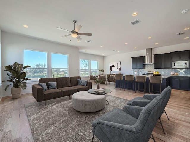 living area featuring light wood-type flooring, recessed lighting, and a ceiling fan