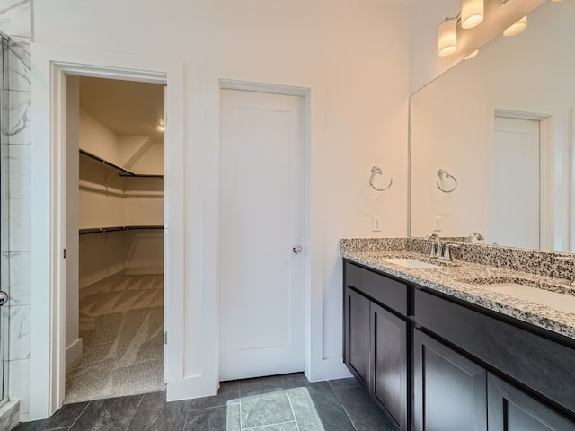 bathroom featuring a spacious closet, a stall shower, double vanity, and baseboards