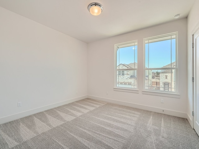 empty room featuring light colored carpet and baseboards