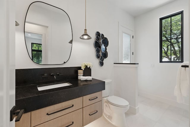 bathroom with plenty of natural light, toilet, vanity, and tile patterned flooring