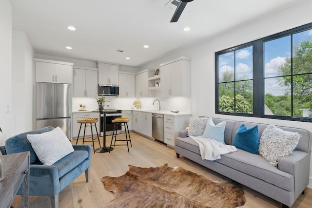 living area with light wood-style flooring, recessed lighting, and a ceiling fan
