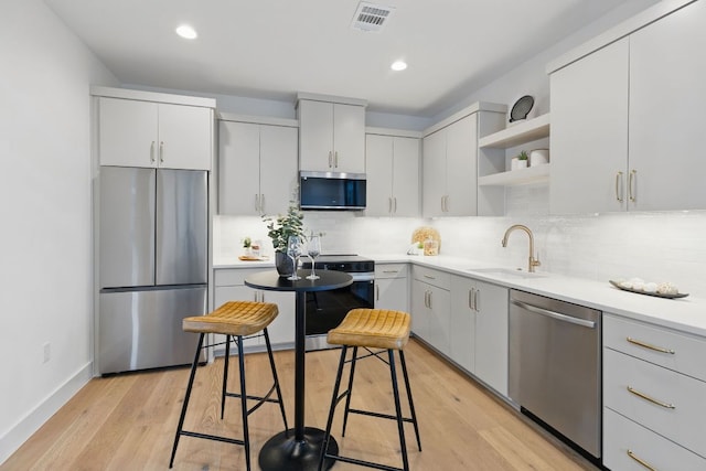 kitchen with appliances with stainless steel finishes, a sink, open shelves, decorative backsplash, and recessed lighting