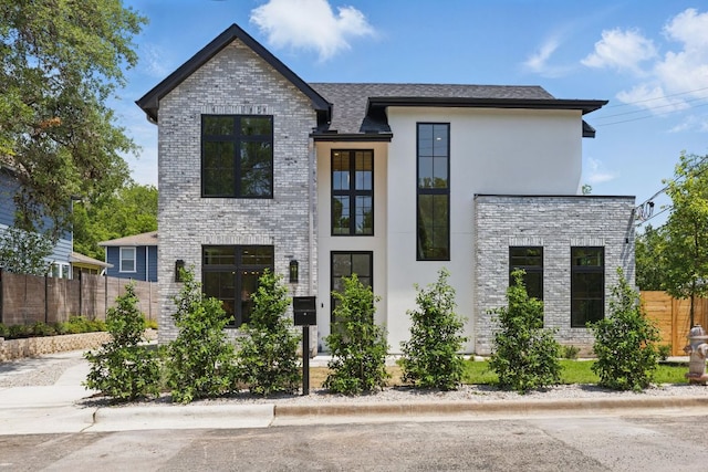 contemporary home featuring fence, stucco siding, and brick siding