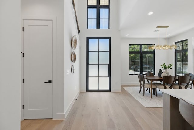 foyer featuring light wood finished floors, a chandelier, baseboards, and recessed lighting