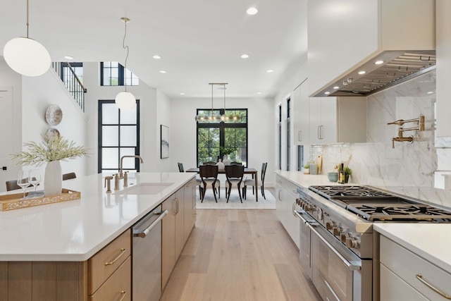 2304 W 8th, Austin, TX 78703 - kitchen featuring appliances with stainless steel finishes, wall chimney range hood, light wood-style flooring, a sink, and light countertops