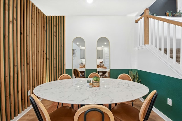 dining space with stairway, wood finished floors, and arched walkways