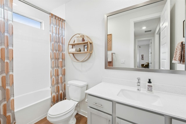 bathroom featuring toilet, wood finished floors, vanity, and shower / bath combo with shower curtain