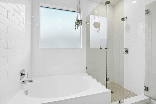 full bathroom with a shower stall, a garden tub, and plenty of natural light