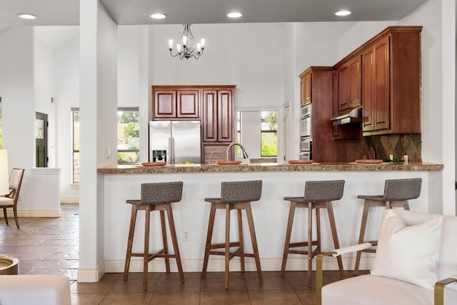 432 Stacey Ann Cv, Dripping Springs, TX 78620 - kitchen with stainless steel appliances, under cabinet range hood, a breakfast bar, a high ceiling, and recessed lighting
