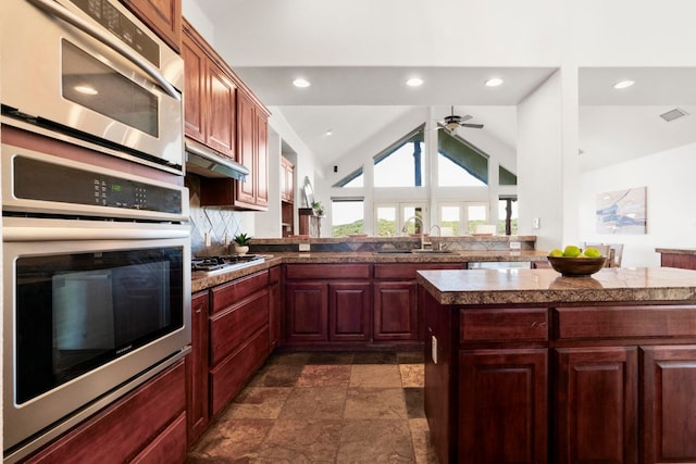 432 Stacey Ann Cv, Dripping Springs, TX 78620 - kitchen featuring stainless steel appliances, tile counters, a ceiling fan, dark stone finish floors, and vaulted ceiling