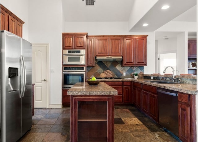 432 Stacey Ann Cv, Dripping Springs, TX 78620 - kitchen with appliances with stainless steel finishes, stone tile flooring, decorative backsplash, under cabinet range hood, and a center island
