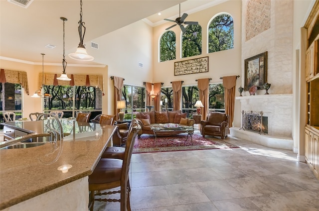 dining area featuring plenty of natural light, ornamental molding, a warm lit fireplace, a ceiling fan, and a towering ceiling