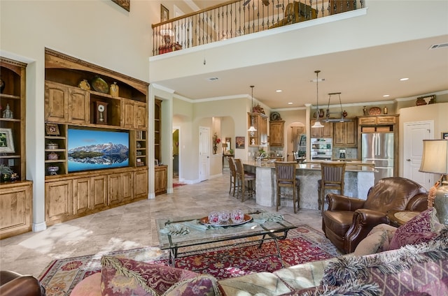 living area with arched walkways, a high ceiling, ornamental molding, recessed lighting, and built in shelves