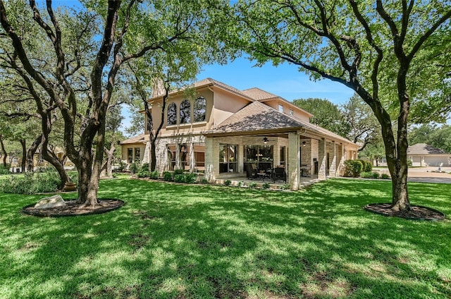back of house with a ceiling fan, a patio area, a lawn, and stucco siding