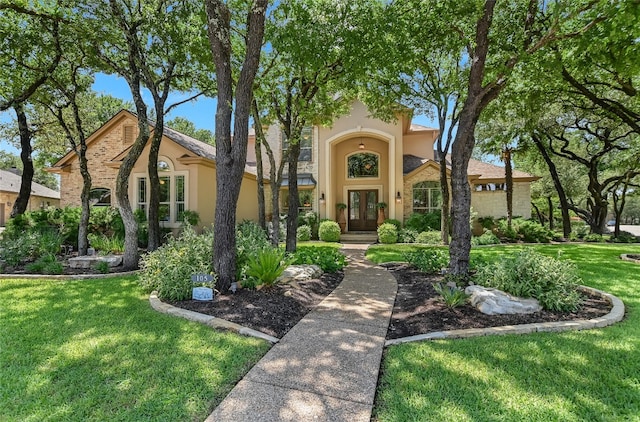view of front of house with french doors, stucco siding, and a front yard