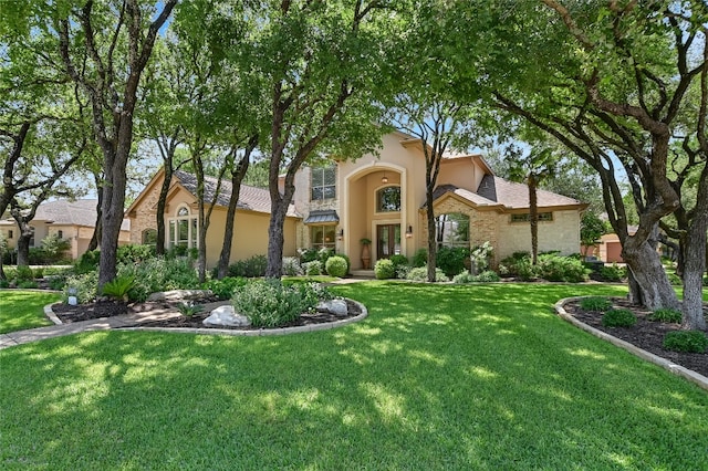 view of front of property featuring stone siding, stucco siding, and a front lawn