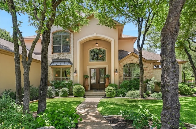 property entrance featuring french doors, stucco siding, and a lawn