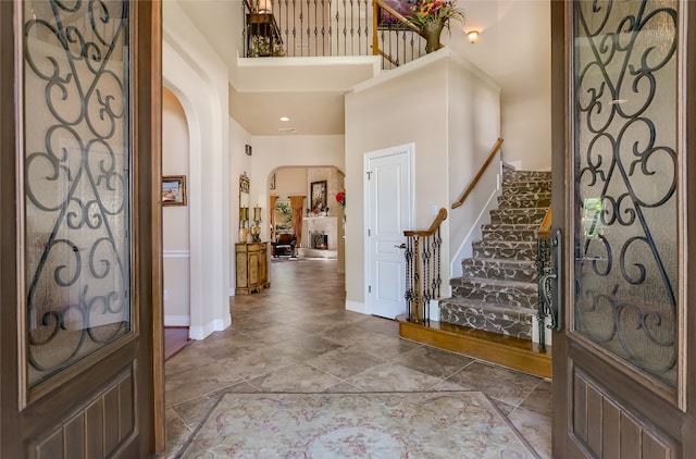 entryway featuring arched walkways, a high ceiling, stairs, and baseboards